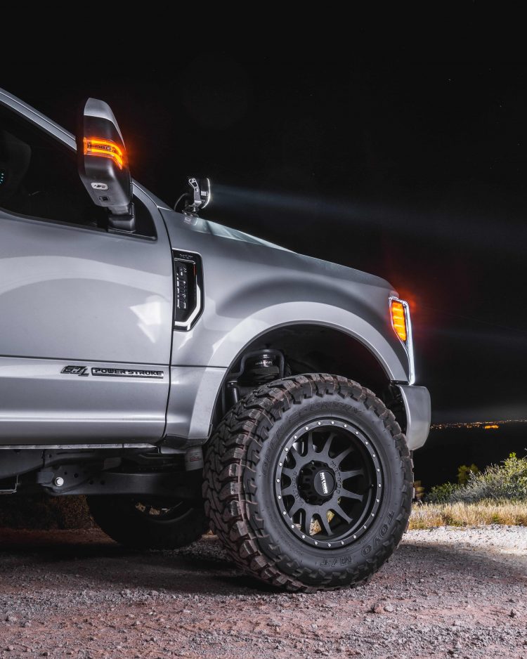 Side profile of an F250 with a lift kit and aftermarket parts and wheels.
