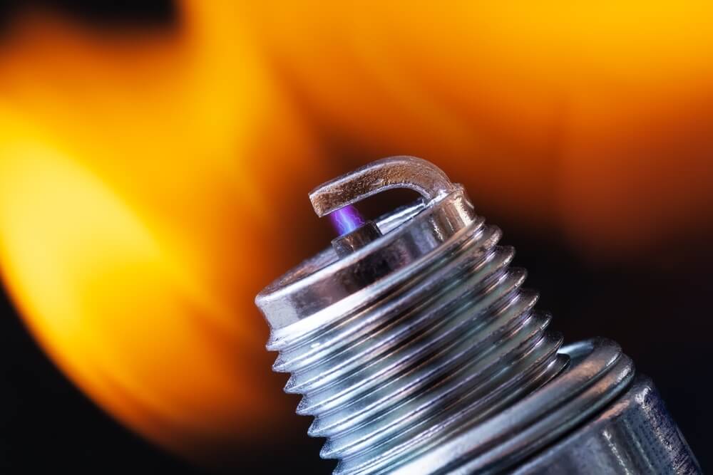 A spark plug firing spark from the electrode to the ground strap.